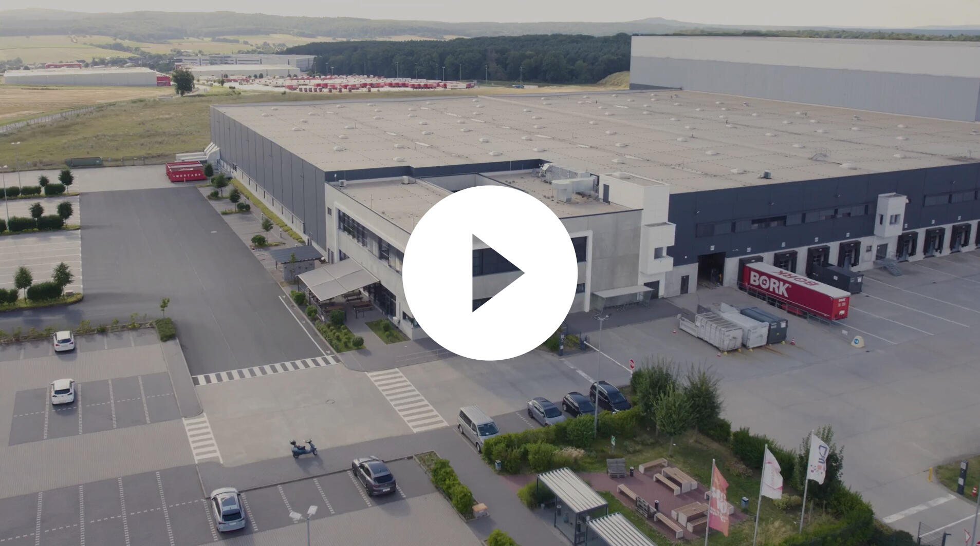 Luftaufnahme eines großen Lagerhauses mit Parkplätzen und Lieferfahrzeugen. | Logistikzentrum Butzbach